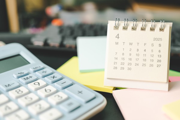 Rekenmachine ligt naast een kalender en een stapel post-its