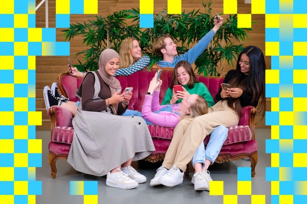 Vriendengroep studenten communicatie die samen hangen in een vintage roze zetel en allemaal bezig zijn op hun smartphone