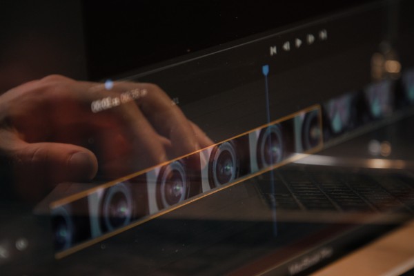 Montagesoftware op laptop met hand op keyboard van laptop gespiegeld in het scherm