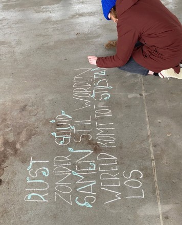 Persoon schrijft gedicht met krijt op de grond